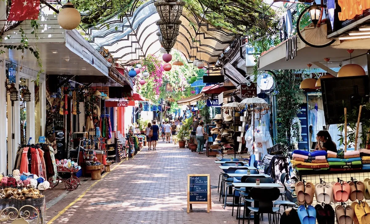 Shaded lane of the Paspatur bazaar in Fethiye old town, with shops, café tables and hanging lanterns